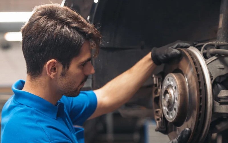 BMW technician working on lifted car in service shop
